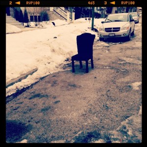 A chair is used as dibs on a snowed-in parking spot.